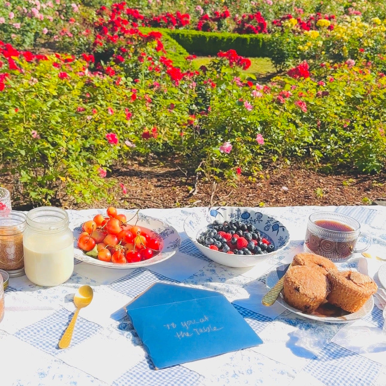Outdoor picnic table with food and drinks in a garden setting