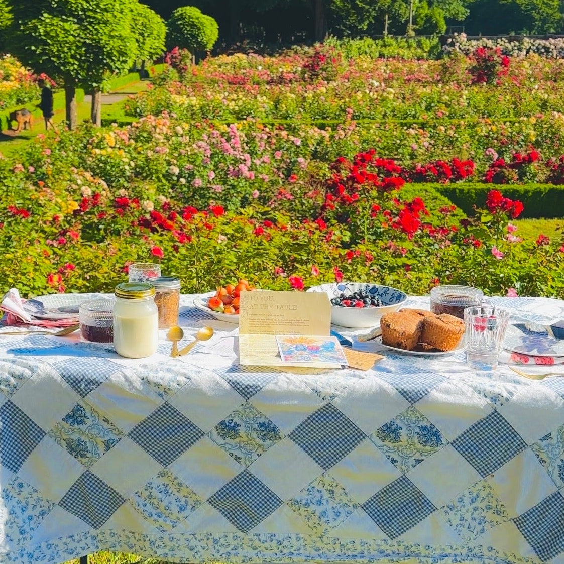 Outdoor setting with a table set for a meal in a garden with flowers and trees.